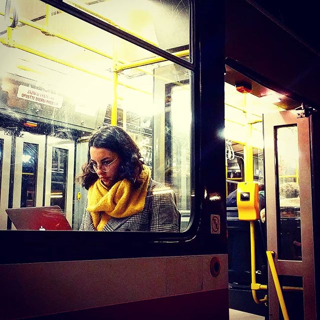 Young woman seated on the tram working on her laptop.