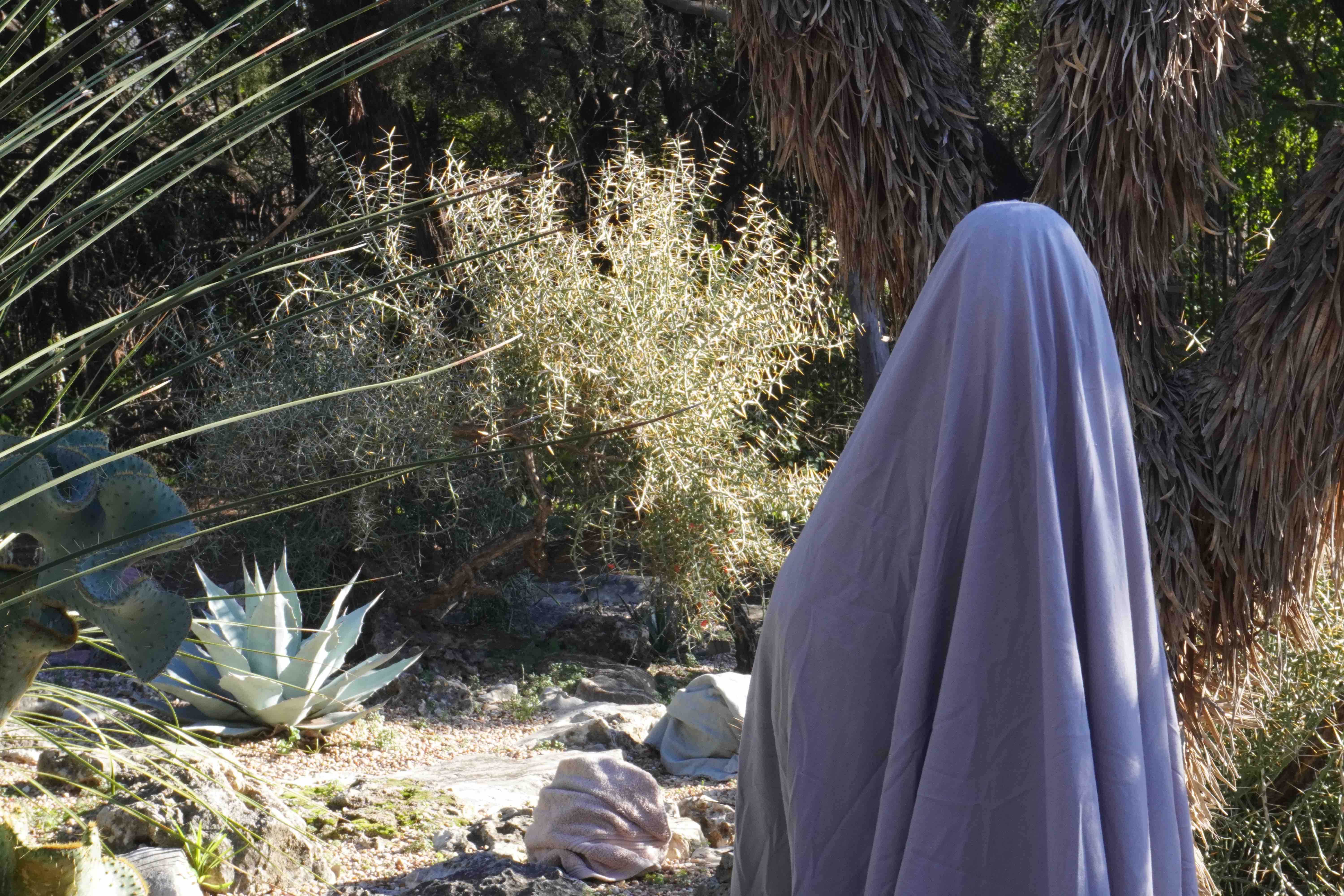 Silhouette of group of young Japanese walking past a bright animated display of a sexualized female character.